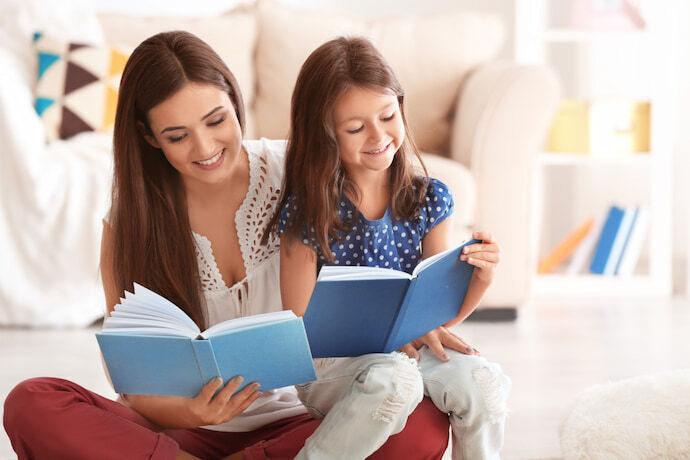 Mãe e filha lendo livros em casa.