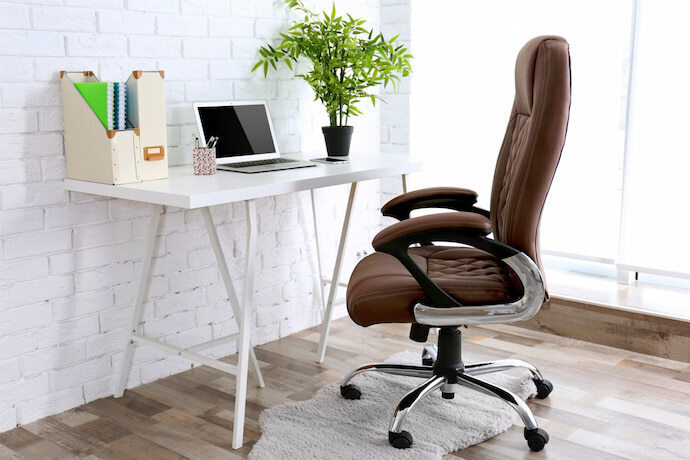 Local de trabalho com mesa branca, cadeira de escritório e objetos de decoração.