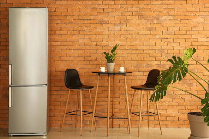 Geladeira inverse em uma cozinha com parede de tijolos