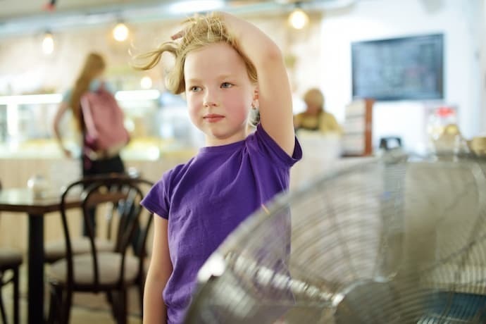 Uma criança aproveitando o vento do ventilador 