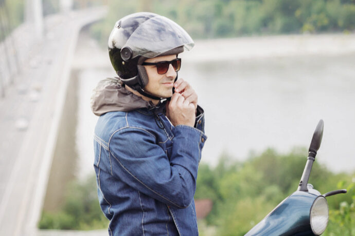 Motoqueiro com capacete olhando para moto