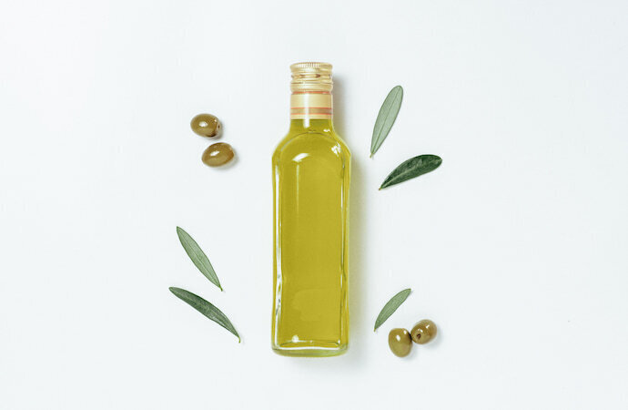 Garrafa de azeite de oliva com azeitonas e folhas de oliveira ao redor