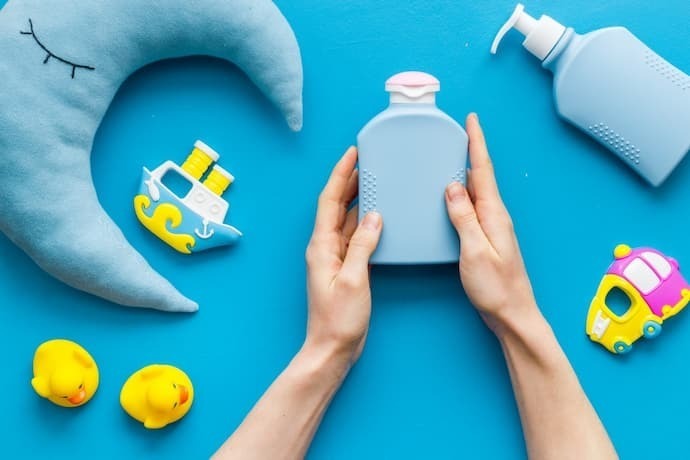 Produtos de higiene para um bebê na mão de uma mulher em um fundo azul