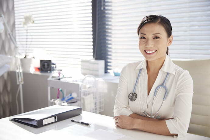 Médica sorrindo em seu consultório 