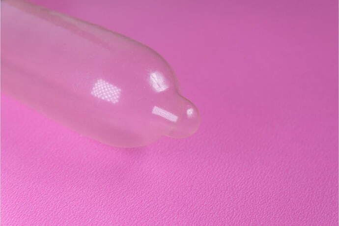 Preservativo de látex em fundo rosa