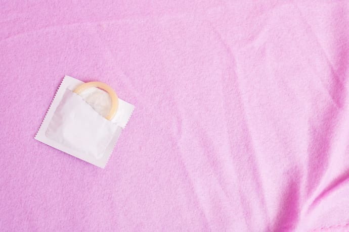 pacote de preservativo no fundo rosa