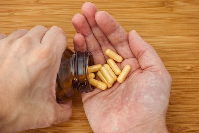 Mão segurando capsulas de vitamina