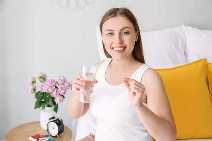 Mulher segurando vitamina e água 