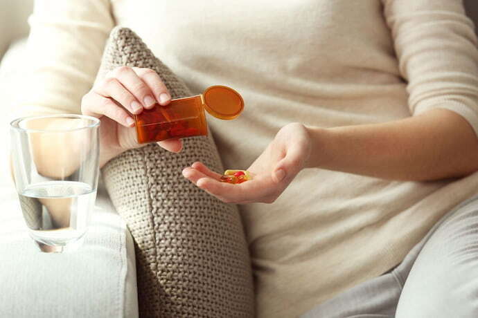 Mulher com capsulas de vitaminas na mão 