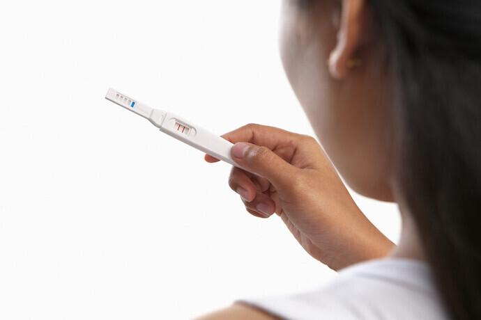 Mulher segurando e olhando teste de gravidez