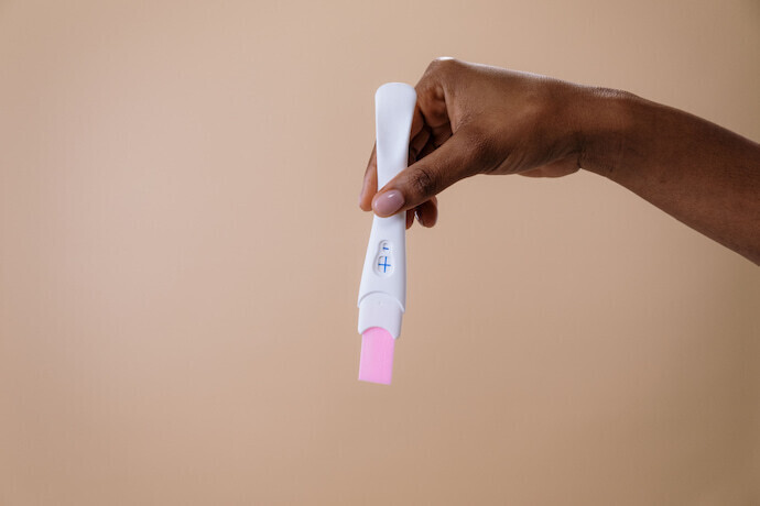 Pessoa segurando teste de gravidez de caneta