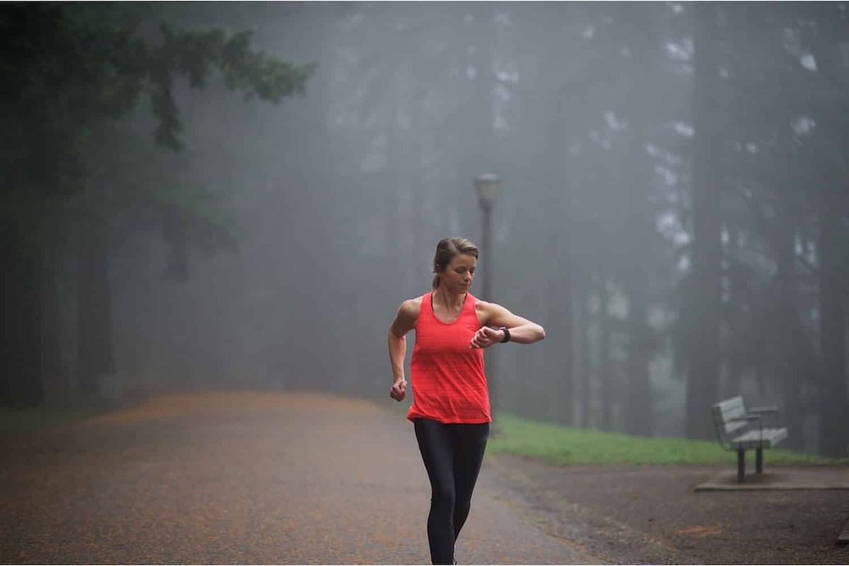 Mulher correndo com smartwatch na chuva