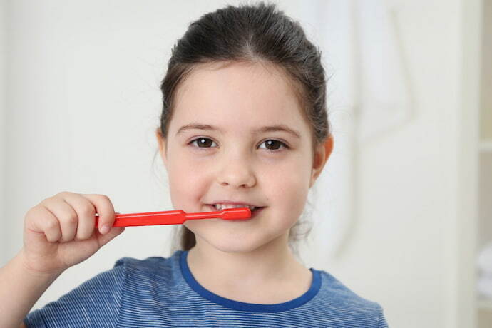 Closeup de garotinha escovando os dentes