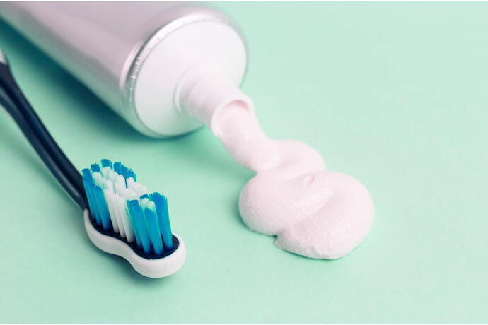 Pasta de dentes em tubo e escova de dentes em fundo azul