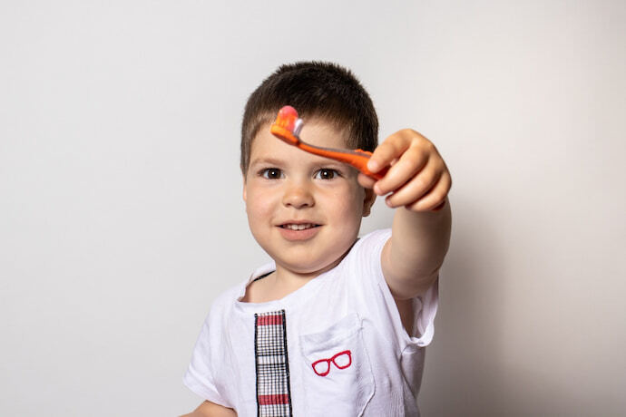 Criança mostrando a escova com pasta de dente