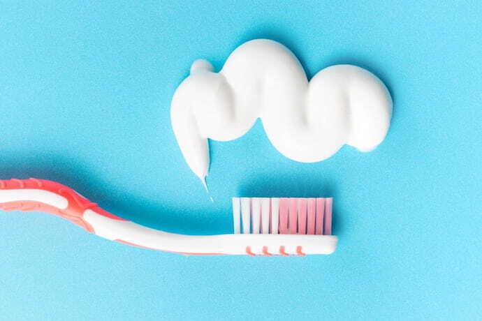 Pasta de dente e uma escova de dente rosa sobre fundo azul