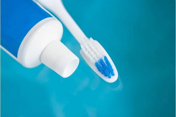 Escova de dente e pasta de dente tubular fecham sobre fundo azul