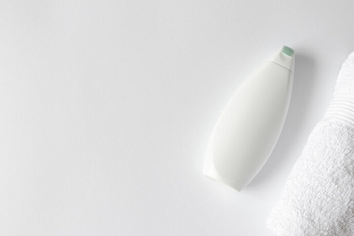 shampoo recipiente plástico em fundo branco e toalha