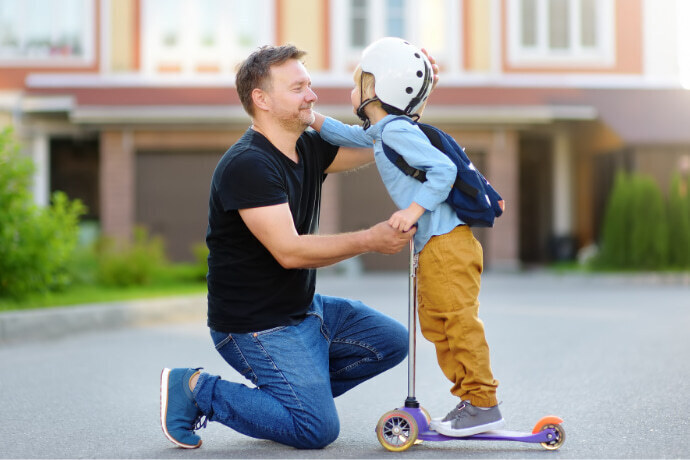 Pai ajudando o filho à andar de patinete