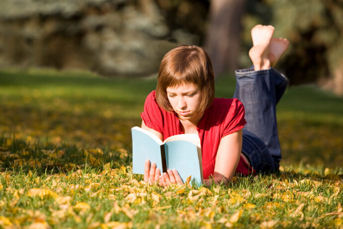 Mulher lendo um livro sobre a grama