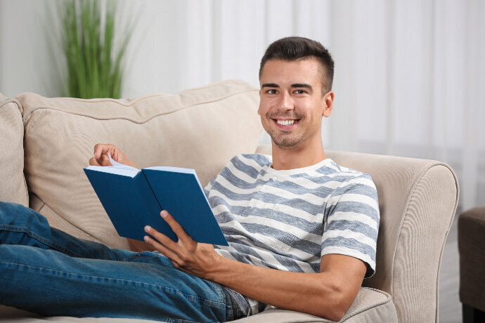 Homem descansando no sofá lendo um livro