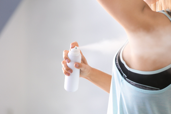 Mulher usando um desodorante em aerosol