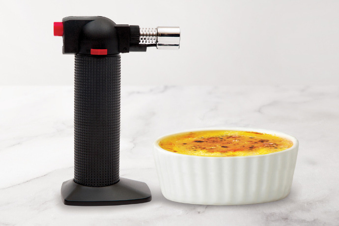Maçarico culinário profissional e uma recipiente com crème brûlée 