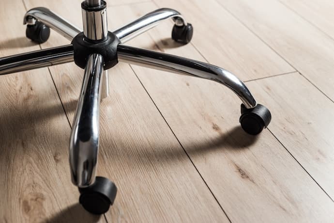 Base de metal da cadeira de escritório com rodas no piso de madeira