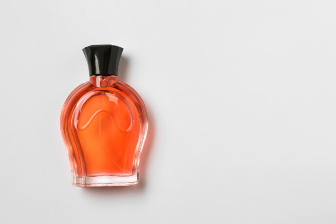 Perfume laranja em frasco transparente e tampa preta
