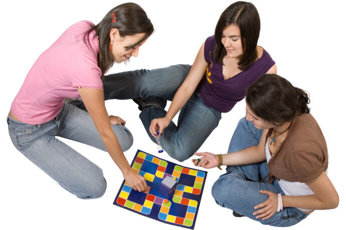 Três  adolescentes jogando um jogo de tabuleiro
