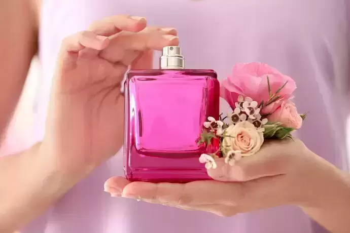 Mulher segurando fraco de perfume e flores