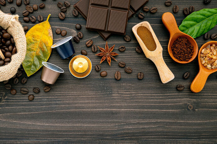 Grãos de café, cápsula e pó em uma superfície de madeira