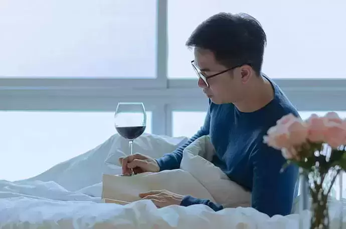 Homem tomando vinho e lendo livro