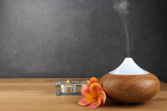 Difusor de aroma, velas e uma flor sobre a mesa