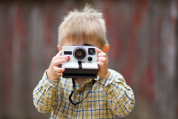 Criança manuseando uma câmera instantânea