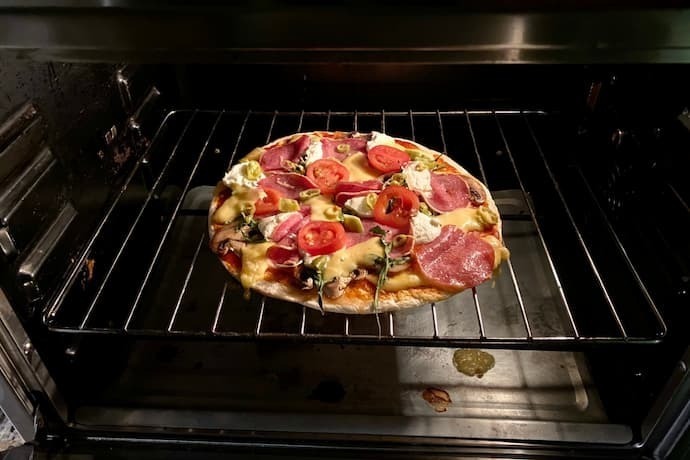 Uma pizza dentro de um forno com grades