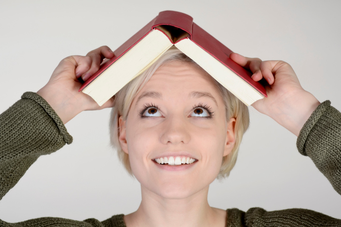 Mulher sorridente com um livro em cima da cabeça