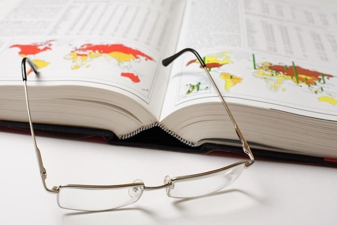Livro aberto de geografia e óculos 
