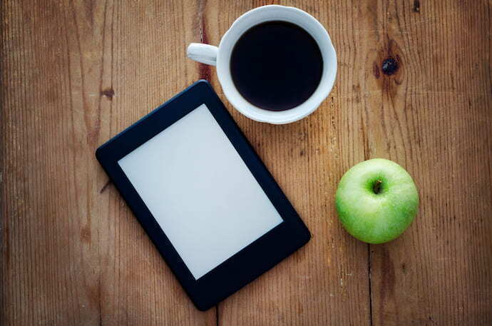 Kindle, copo de café e maça