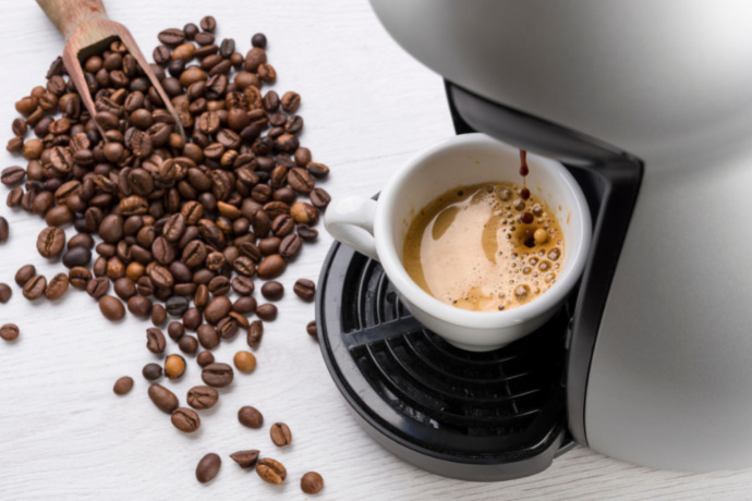 Cafeteira, uma xícara de café da Nespresso e grãos de café