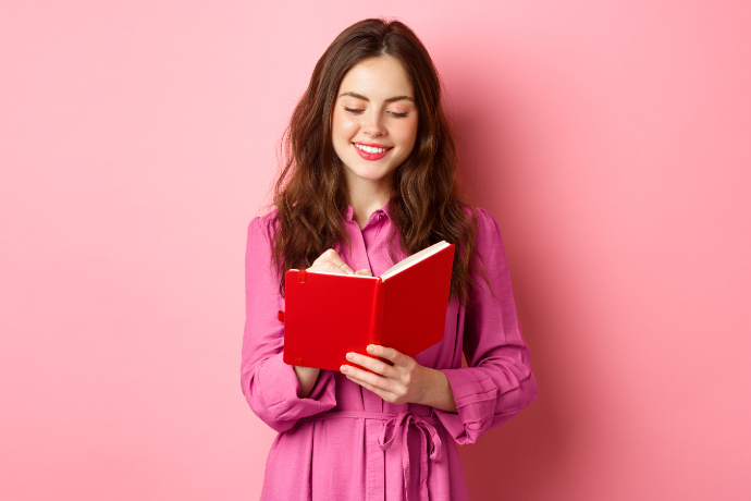 Mulher lendo um livro em um fundo rosa