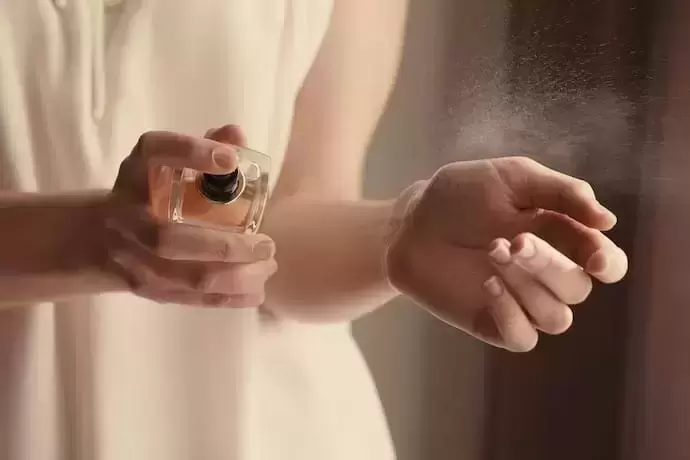 Mulher aplicando perfume nos pulsos