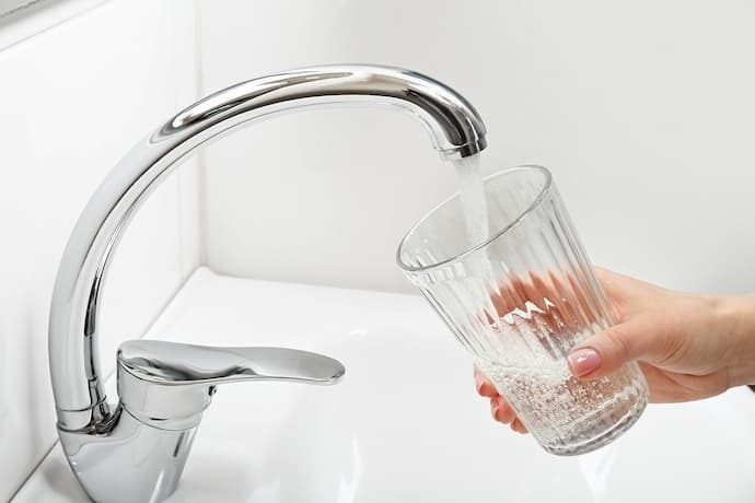 Pessoa enchendo copo de água na torneira