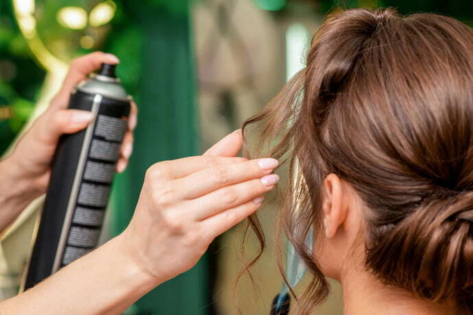 Cabeleireiro aplicando spray de cabelo no cabelo