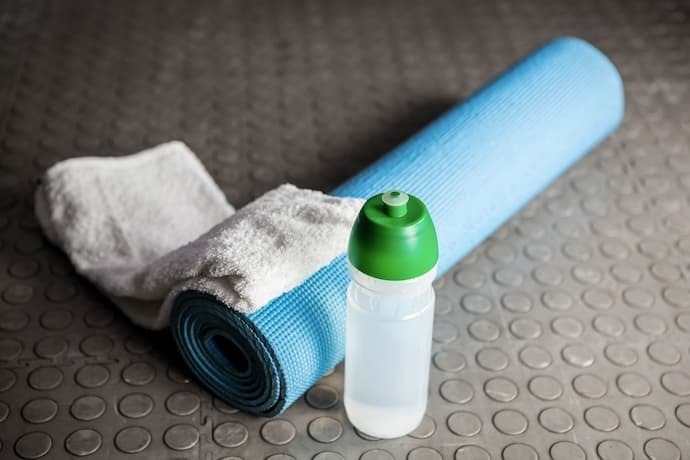 Tapete para exercícios, toalha e garrafa de água no chão