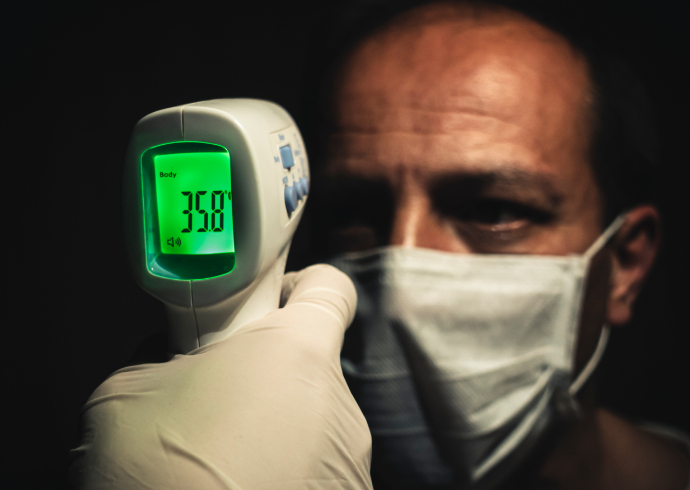 Indivíduo medindo a temperatura de um homem com o termômetro infravermelho 