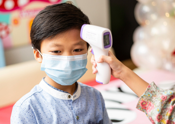 Indivíduo medindo a temperatura de uma criança com o termômetro infravermelho 