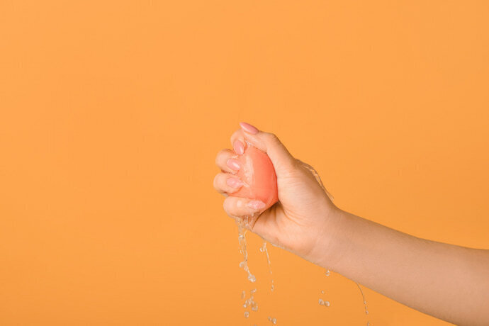 Mão espremendo esponja com água