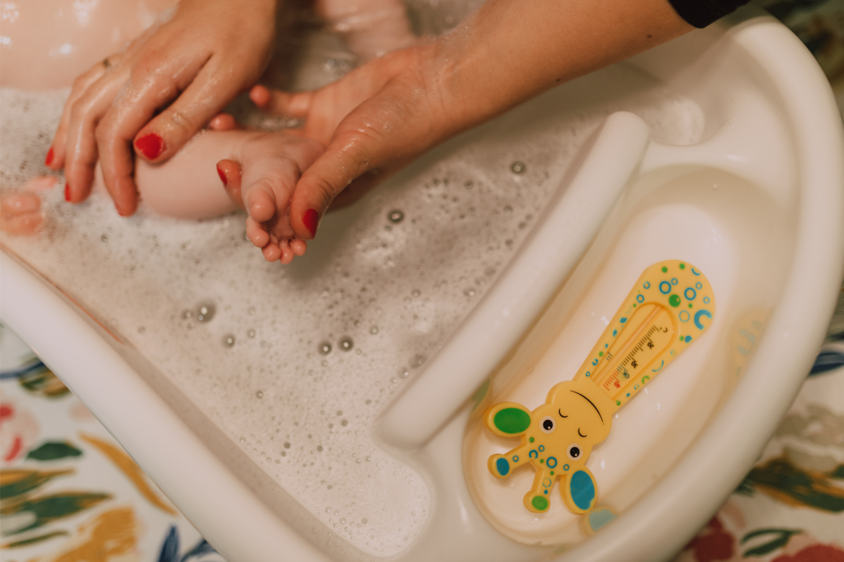 mãos de adulto lavando pé de bebê em uma banheira infantil