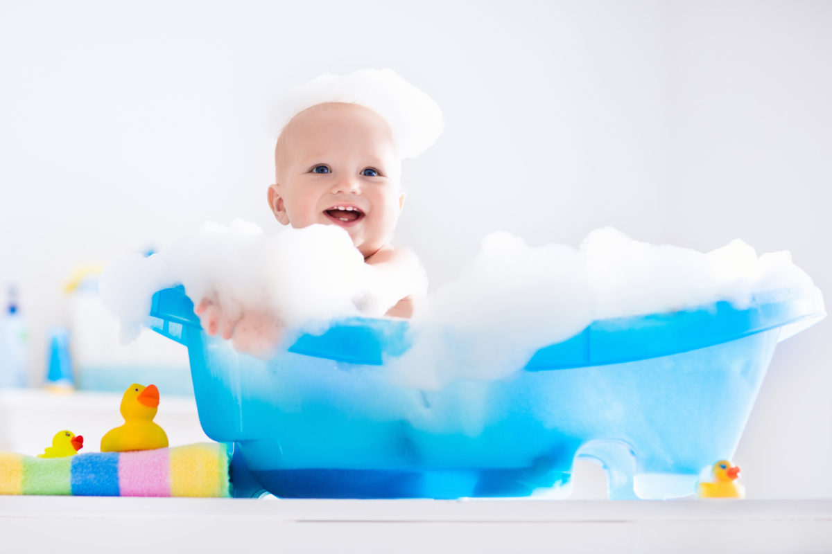 bebê em uma banheira azul cheio de espuma e sorrindo